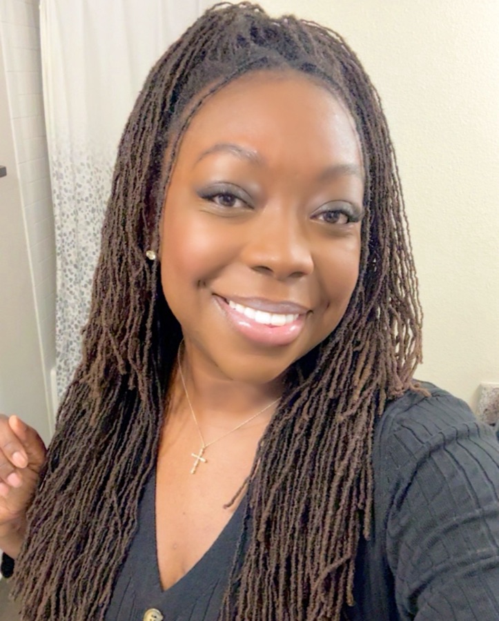Brittany smiling in a black ribbed cardigan and gold cross necklace